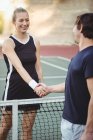 Joueurs de tennis souriants serrant la main dans le court avant le match — Photo de stock