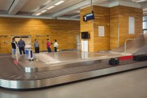 Menschen, die in der Gepäckausgabe am Flughafen auf ihr Gepäck warten — Stockfoto