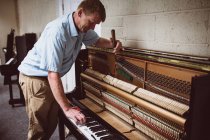 Técnico de piano reparando piano de madera en taller - foto de stock