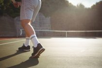 Baixa seção de homem jogando tênis na corte em luz suave — Fotografia de Stock