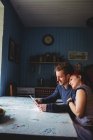 Sonriendo joven pareja hipster utilizando tableta digital mientras está sentado en la mesa en casa - foto de stock