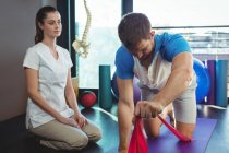 Female physiotherapist assisting male patient while exercising in clinic — Stock Photo