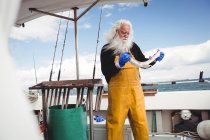 Pescatore che tiene il pesce in barca — Foto stock