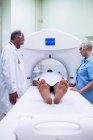 Patient entering mri machine with doctors at hospital — Stock Photo