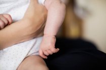 Cropped image of Mother holding baby at home — Stock Photo