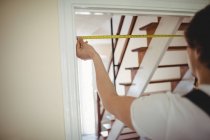 Zugeschnittenes Bild eines Zimmermanns, der einen Türrahmen zu Hause misst — Stockfoto