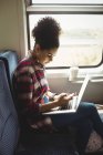 Vue latérale de la femme utilisant le téléphone avec ordinateur portable tout en étant assis dans le train — Photo de stock