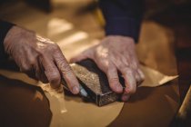 Hände des Schuhmachers, der in der Werkstatt ein Stück Leder schneidet — Stockfoto