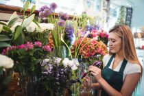 Floristería femenina arreglando flores en su floristería - foto de stock