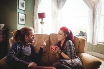 Jovem casal hipster conversando no sofá em casa — Fotografia de Stock