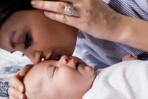 Mother kissing her baby on forehead while he sleeping in living room at home — Stock Photo