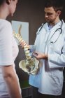 Physiothérapeute expliquant la colonne vertébrale au patient en clinique — Photo de stock