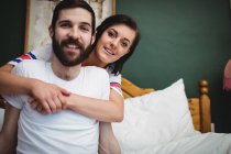 Женщина обнимает мужчину на кровати в спальне — стоковое фото