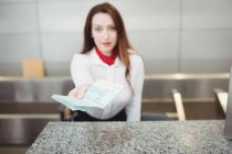 Asistente de facturación de aerolínea que da pasaporte en el mostrador de facturación del aeropuerto - foto de stock
