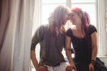 Happy young couple romancing against window at home — Stock Photo