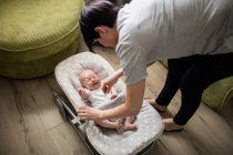 Mother consoling her crying baby in stroller in living room at home — Stock Photo