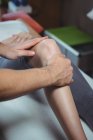 Обрізане зображення фізіотерапевта, що дає фізичну терапію колінному суглобу пацієнта в клініці — стокове фото