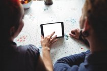 Image recadrée d'un couple utilisant une tablette numérique à la maison — Photo de stock