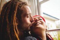 Jovem casal hipster abraçando pela janela em casa — Fotografia de Stock