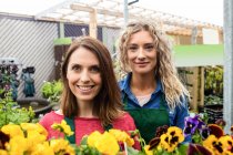 Портрет двух женщин-флористок, улыбающихся в центре сада — стоковое фото