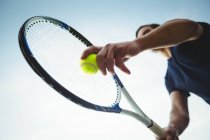 Низький кут зору людини з тенісною ракеткою, готовою служити в суді — стокове фото