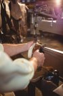 Mains de cordonnier utilisant une machine à coudre en atelier — Photo de stock