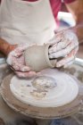 Sección media de alfarero haciendo olla en taller de cerámica - foto de stock