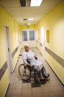 Thoughtful senior woman sitting on wheelchair in hospital corridor — Stock Photo
