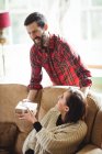 Mann überrascht Frau mit Geschenk im heimischen Wohnzimmer — Stockfoto