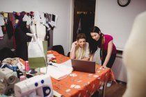 Женщины-модельеры, работающие над ноутбуком в студии — стоковое фото