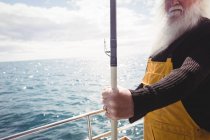 Обрізане зображення рибалки, що тримає рибальський стрижень на човні — стокове фото