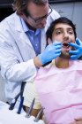 Dentist examining a patient with angle mirror in dental clinic — Stock Photo
