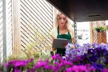 Писательница-флористка на планшете в центре сада — стоковое фото