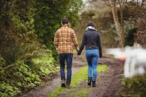 Rear view of couple walking on dirt track in countryside — Stock Photo
