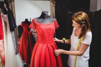 Творческий дизайнер настраивает платье на манекен — стоковое фото