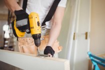 Cropped image of Carpenter tightening screw to hinges on wooden door at home — Stock Photo