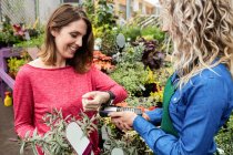 Woman making payment through smart watch in garden centre — Stock Photo