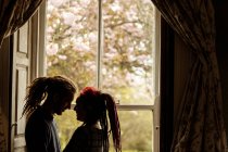 Vista lateral de pareja joven y romántica de pie junto a la ventana en casa - foto de stock