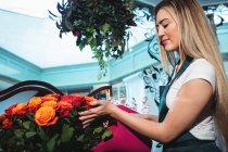 Fiorista femminile versando acqua in vaso di fiori al suo negozio di fiori — Foto stock