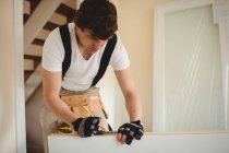Carpenter measuring wooden door with pencil at home — Stock Photo