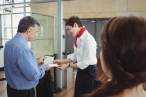Бизнесмен показывает посадочный талон на стойке регистрации в аэропорту — стоковое фото