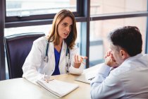Doctor at desk talking to patient in hospital — Stock Photo