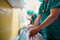Gruppo di chirurghi che si lavano le mani al lavabo in ospedale — Foto stock