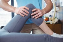 Обітнутого зображення чоловічого фізіотерапевт, даючи коліно масаж пацієнтки в клініці — стокове фото