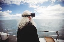 Vista trasera de Fisherman usando auriculares de realidad virtual en barco de pesca - foto de stock