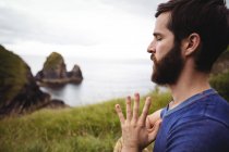 Close-up of man performing yoga on cliff — Stock Photo