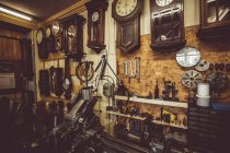 Ancien atelier d'horlogerie avec des outils de réparation d'horloge, des équipements et des horloges sur le mur — Photo de stock