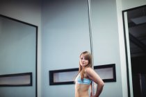 Porträt einer Pole-Tänzerin, die sich im Fitnessstudio an die Stange lehnt — Stockfoto