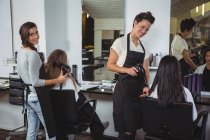 Las mujeres que se secan el cabello con secador de pelo en el salón de belleza - foto de stock