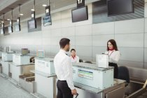 Airline check-in attendants checking passport of passenger at airport check-in counter — Stock Photo